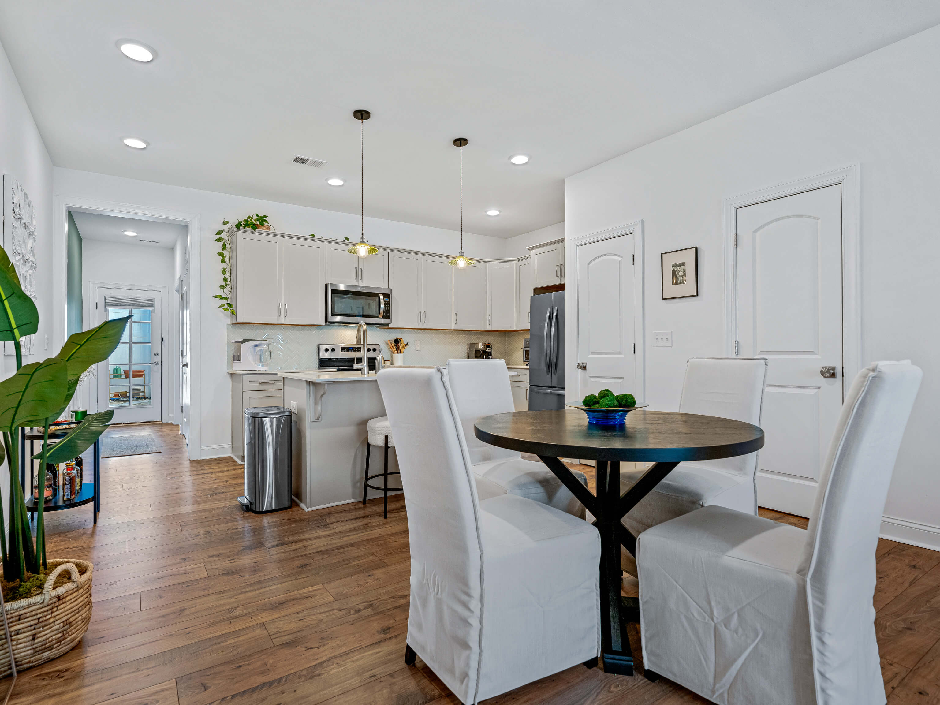 Dining area with round table and white chairs adjacent to kitchen