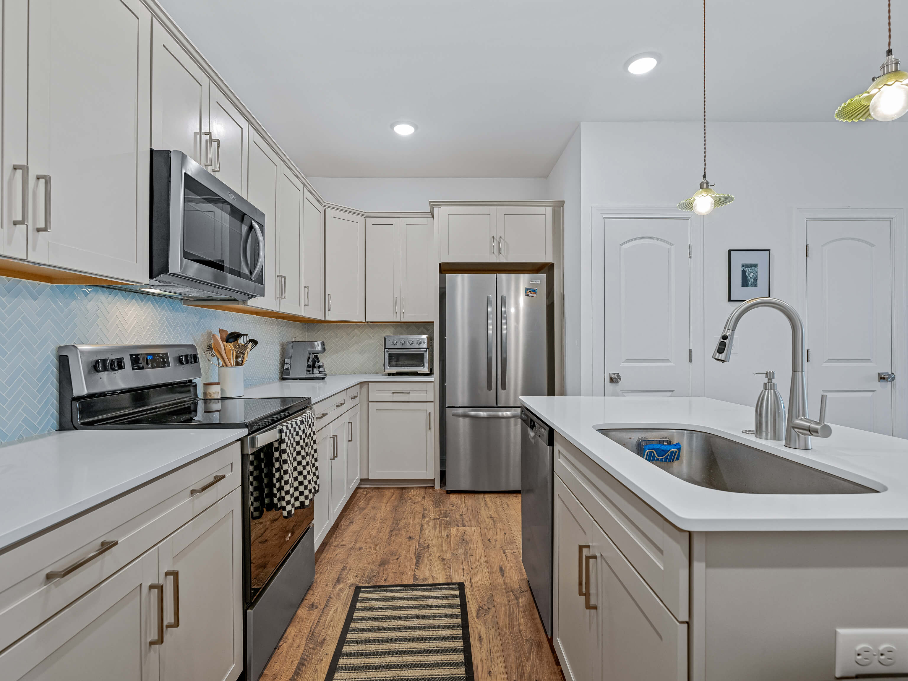 Galley kitchen with blue herringbone backsplash and white cabinets
