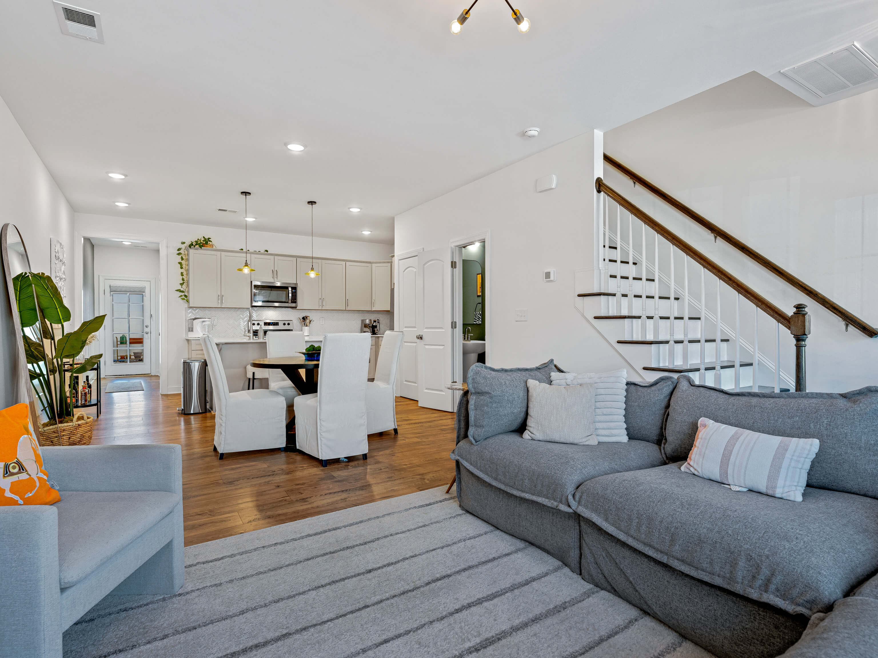 Open-concept main living area with staircase, kitchen, dining, and living room
